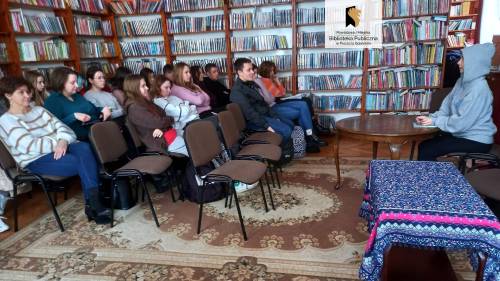 Widok na scenę oraz uczniów. W tle widać zbiory biblioteczne.